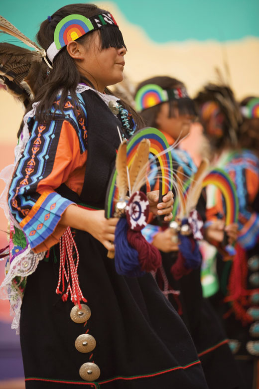 Group of children wearing colorful outfits and holding dreamcatchers.