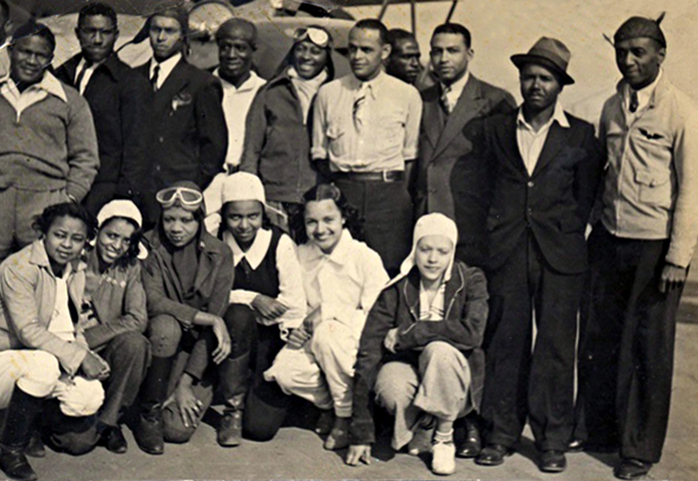 Group of people posed in front of an airplane.