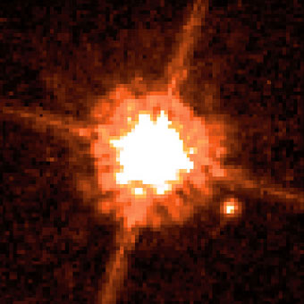 View through a telescope that shows a tiny planet close to a star. 