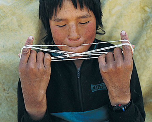 Young Native American uses a piece of string to play cat's cradle.