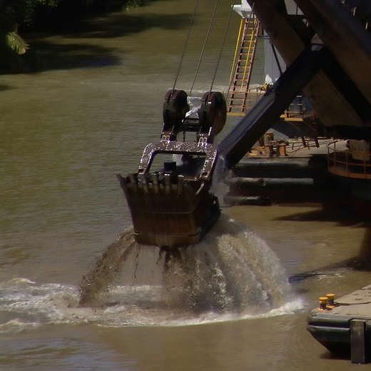 Piece of equipment pulls up dirt and rock from the bottom of the river.