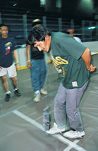 Native American man carrying weights on a string attached to his ears.