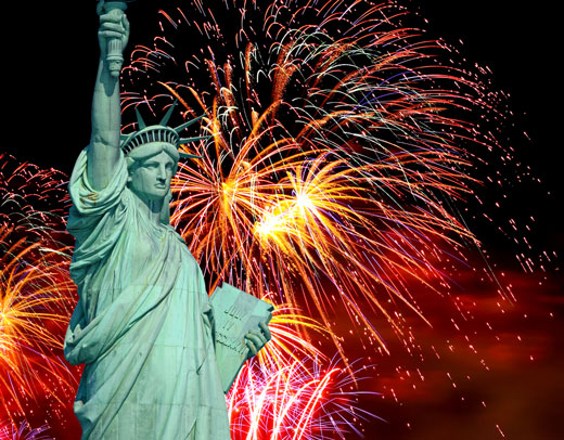 The Statue of Liberty with fireworks going off behind it.