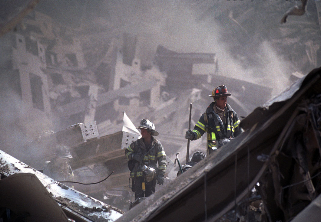 Two firefighters stand amid debris from the World Trade Center.