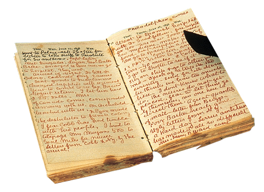 A worn, open journal with red handwritten notes.