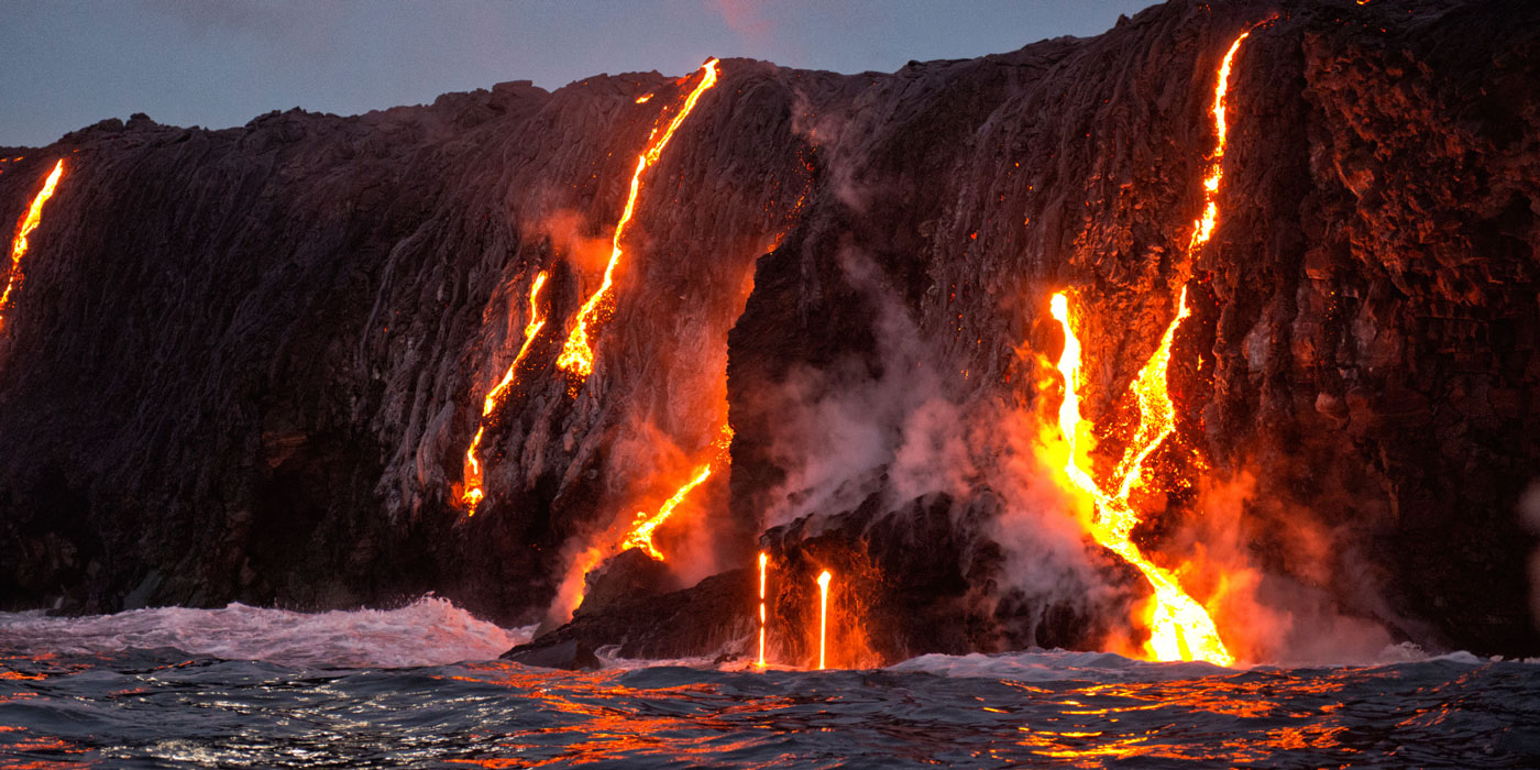 Lava from a volcano in Hawaii flows down the side of the volcano and into the ocean.