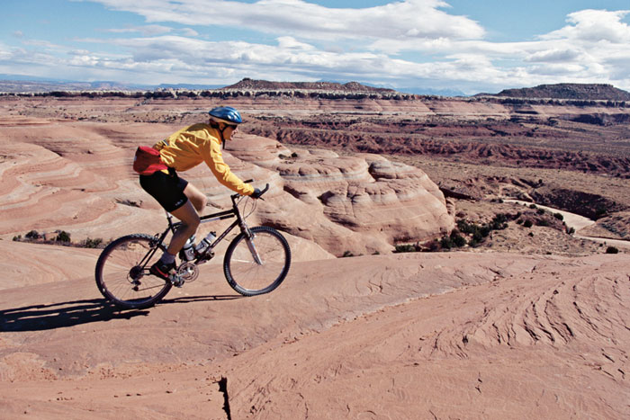 Person riding a bike along the top of the Grand Canyon.