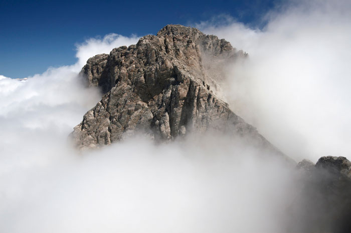 Top of a mountain seen sticking out of the clouds.
