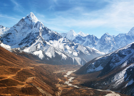 Tall mountain is shown with snow on its peak.