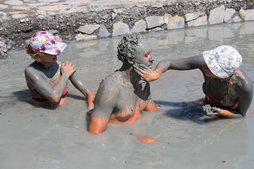 People taking mud baths in a pool of water.
