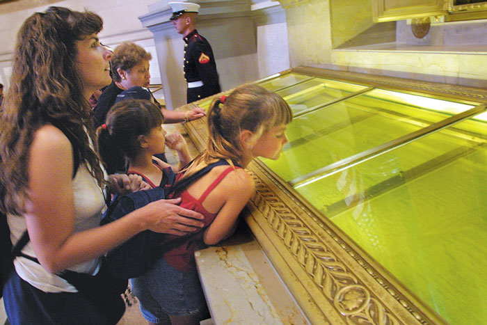 A mom holds her small daughter up so she can look at the Declaration of Independence, which is under glass.