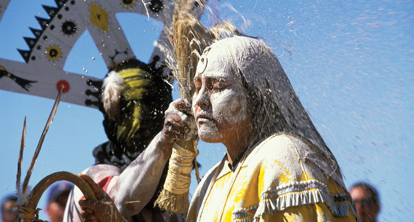 Native girl covered with mud and being struck in the head with corn pollen.