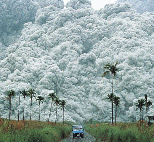 Large cloud of gas is seen behind a vehicle driving down a road.