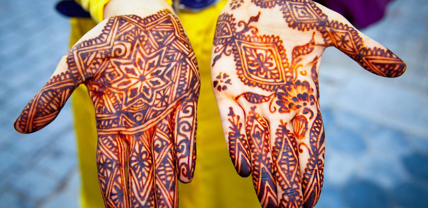 Person's hands covered with intricate designs made by henna. 