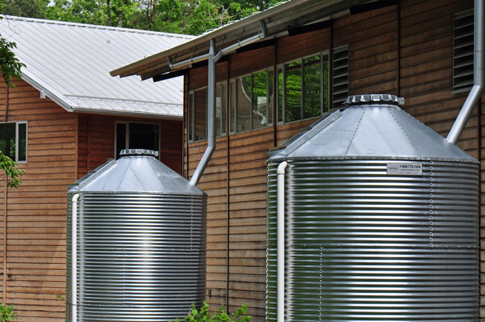 Two large water tanks attached to a building from its gutters.