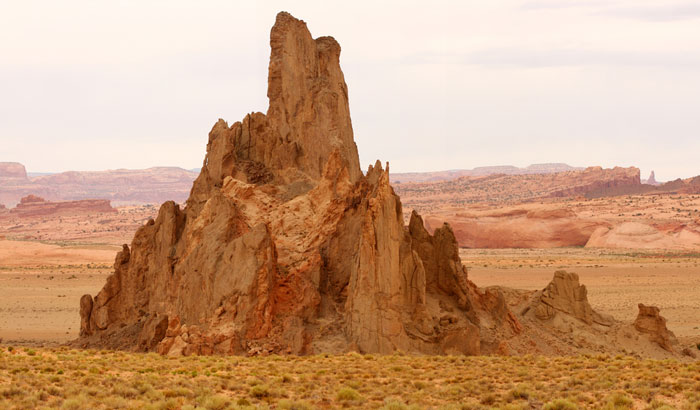 Large rock formation sticks up out of the floor of the desert.