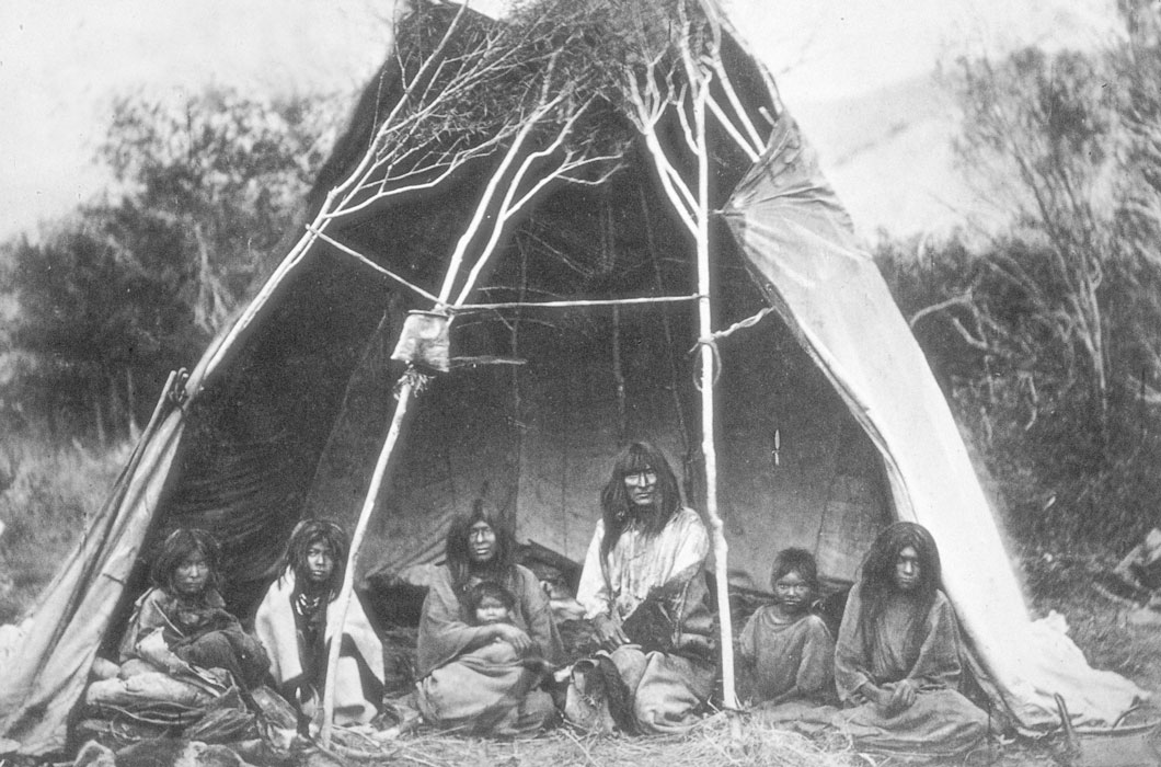 Native American family sitting in a teepee.