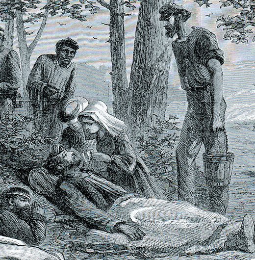 A woman helps a man lying on the ground while others stand by.