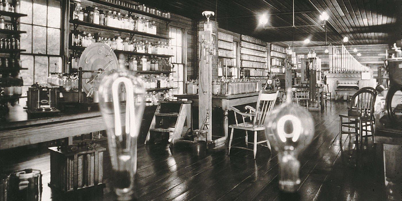 Close up of two illuminated light bulbs sitting on a table in a workshop.