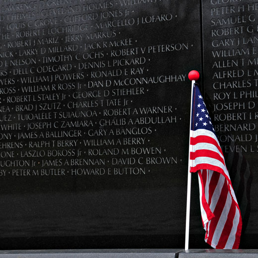 American flag in front of a stone monument.
