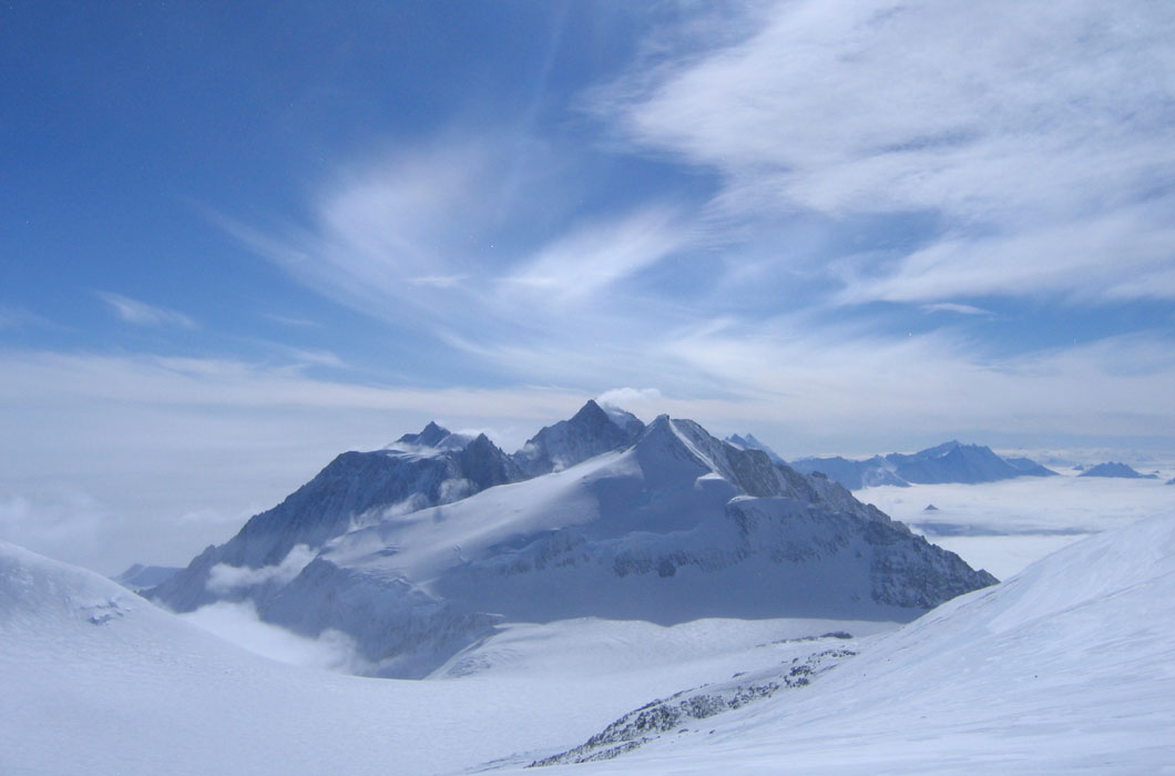 Mountain sticks up out of a vast frozen desert. 
