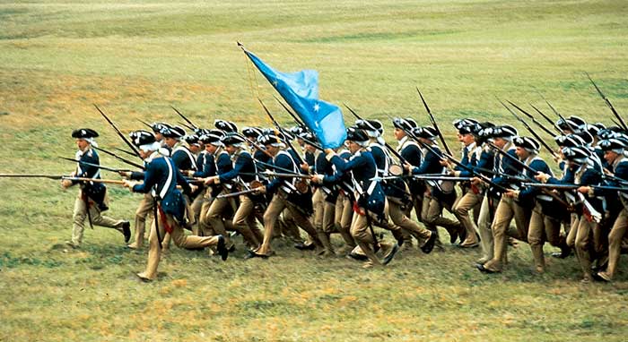 Many modern colonial soldiers in formation advance with their muskets pointed. 