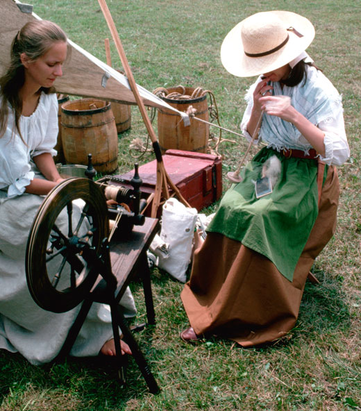 Two modern women reinacting the War by sitting in front of a sewing machine sewing.