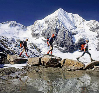 Three hikers walk across rocks in the mountains.