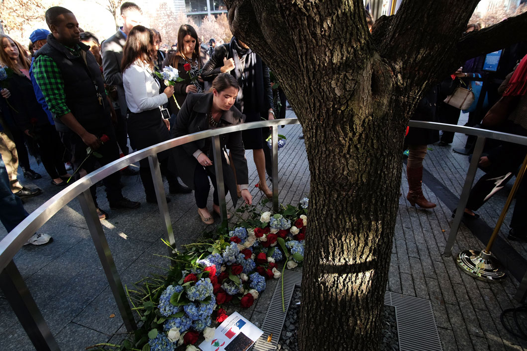 People placing flowers around a tree.