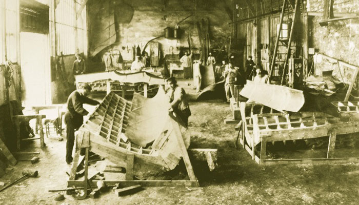 Photo of workers in a large workroom constructing parts of the model from wood and plaster.